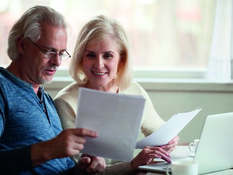 Happy older aged couple holding reading good news in document